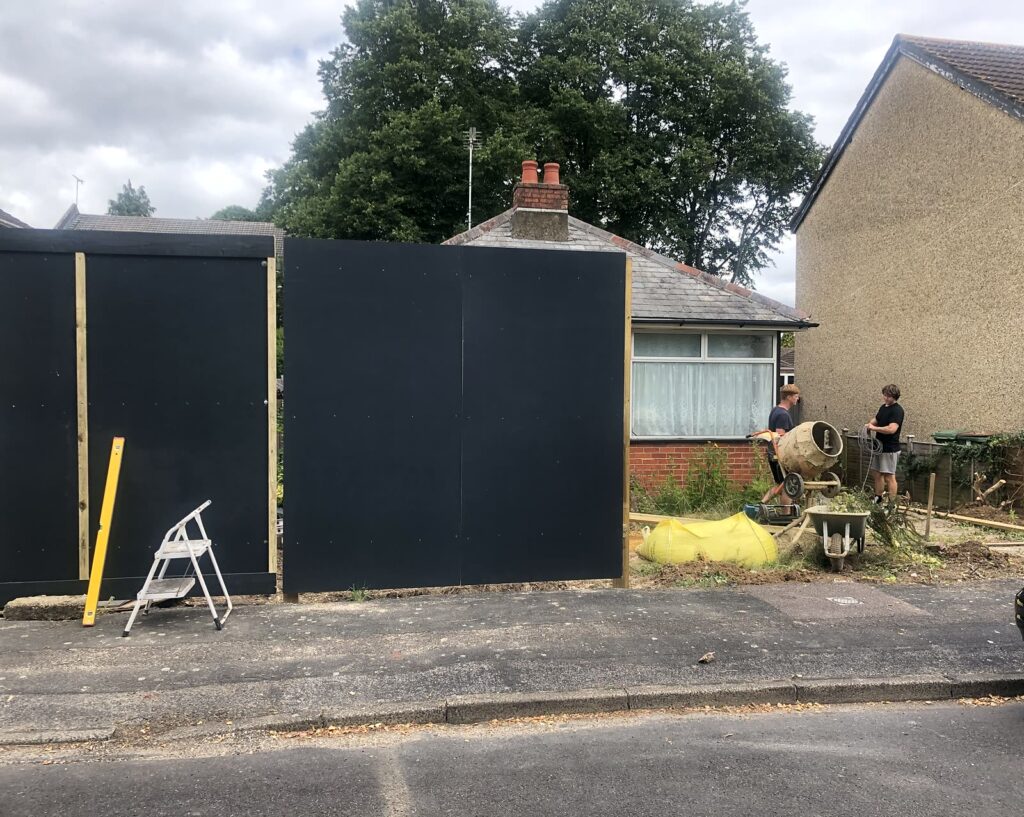 Project story: from old bungalow to two new family homes in Eastleigh Site hoarding going up in front of the old bungalow