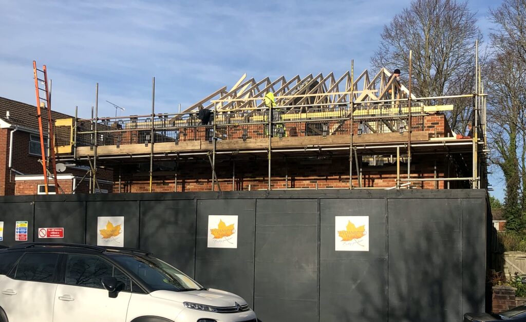 Project story: from old bungalow to two new family homes in Eastleigh Roof trusses going on behind our Maidanbuild site hoarding